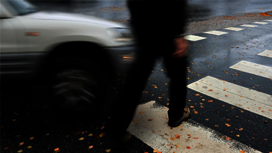 Pedestrian dressed in black crossing the street