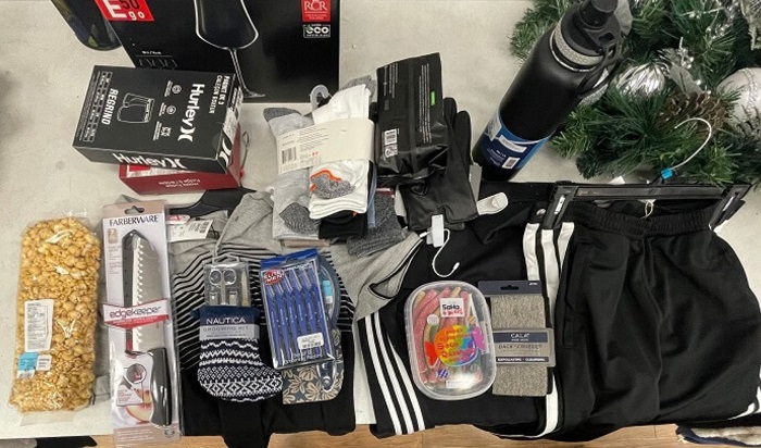 Recovered merchandise on table including clothing, knife, water bottle, grooming items, candy